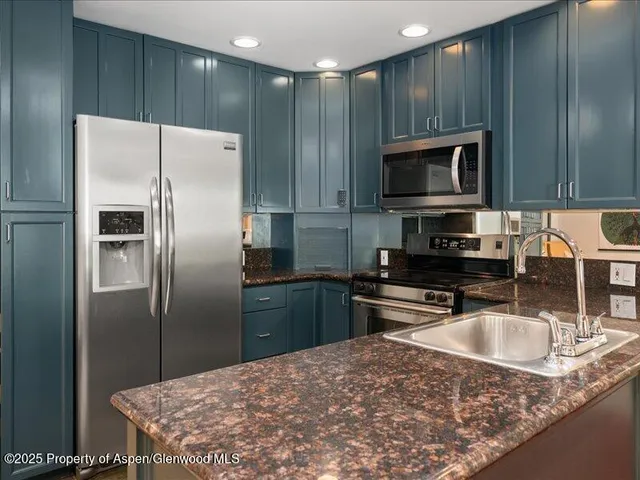 a kitchen with kitchen island granite countertop a sink stove and refrigerator