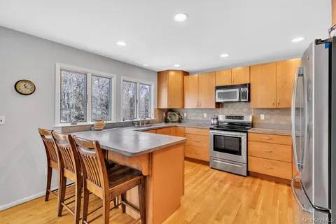 a kitchen with stainless steel appliances granite countertop a stove top oven a sink a refrigerator with a dining table and chairs