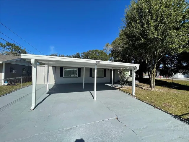 a view of a house with a yard and large tree