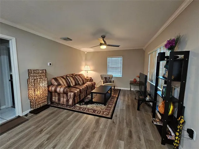 a living room with furniture a flat screen tv and a wooden floor