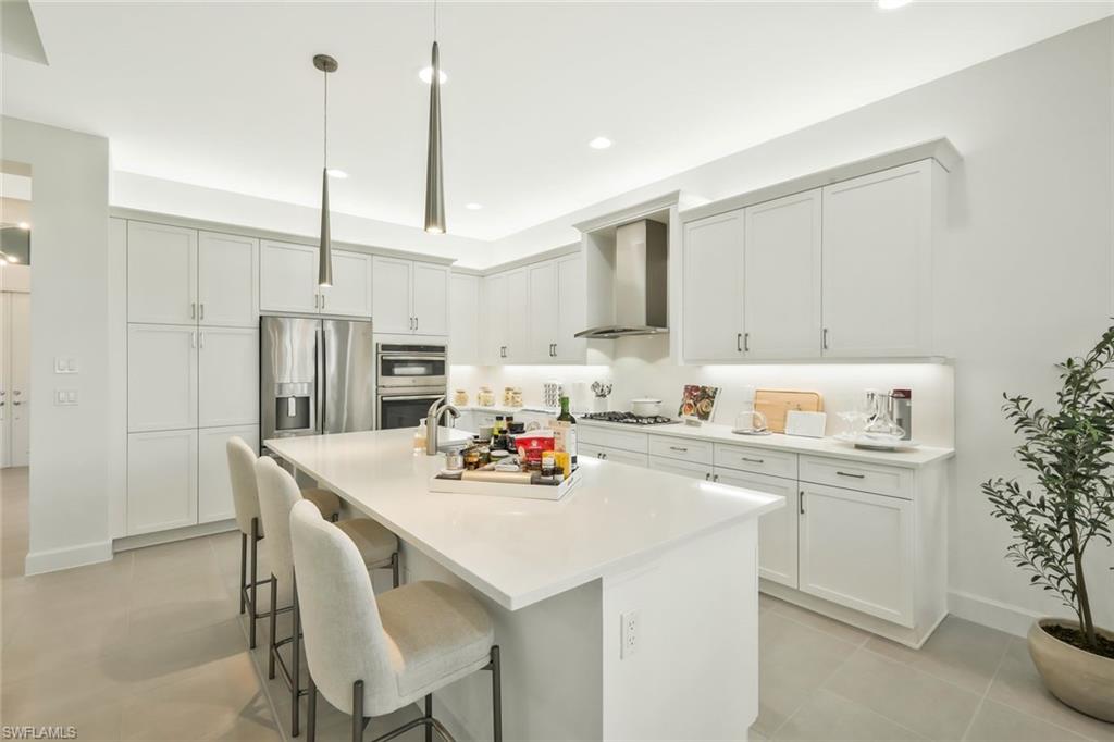 11805 Drake Lane Naples, FL 34120 - Photo 12 of 30 a kitchen with stainless steel appliances a sink a stove a refrigerator cabinets and dining table