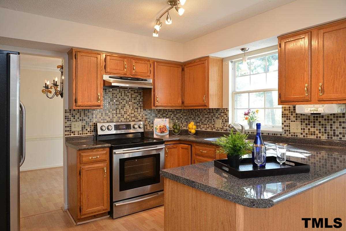 Trendy glass tile backsplash with stainless steel kitchen appliances and an updated laminate countertops in this bright kitchen!