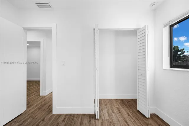 a view of a hallway with wooden floor windows and a bathroom