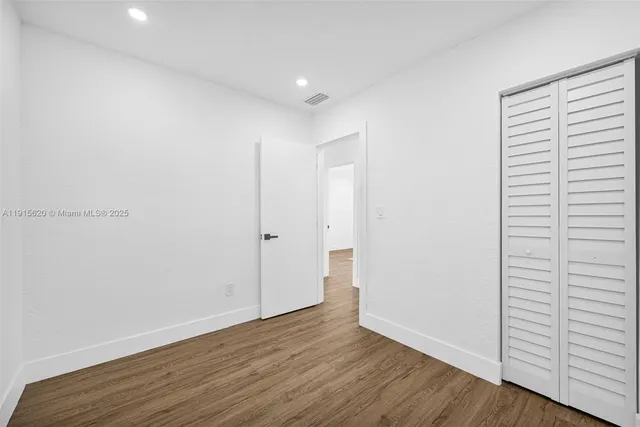 an empty room with wooden floor and closet