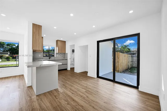 a kitchen with stainless steel appliances kitchen island wooden floors and white walls