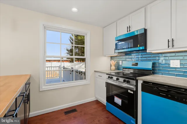 a kitchen with stainless steel appliances granite countertop a refrigerator a sink dishwasher a stove top oven a kitchen island and chairs with wooden floor