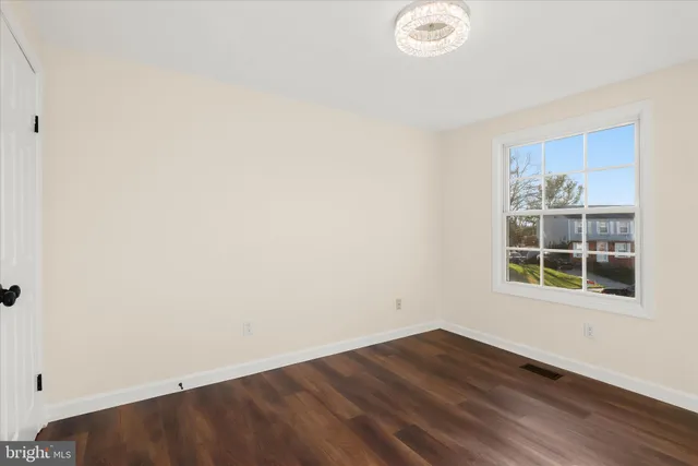 a view of an empty room with wooden floor fireplace and a window