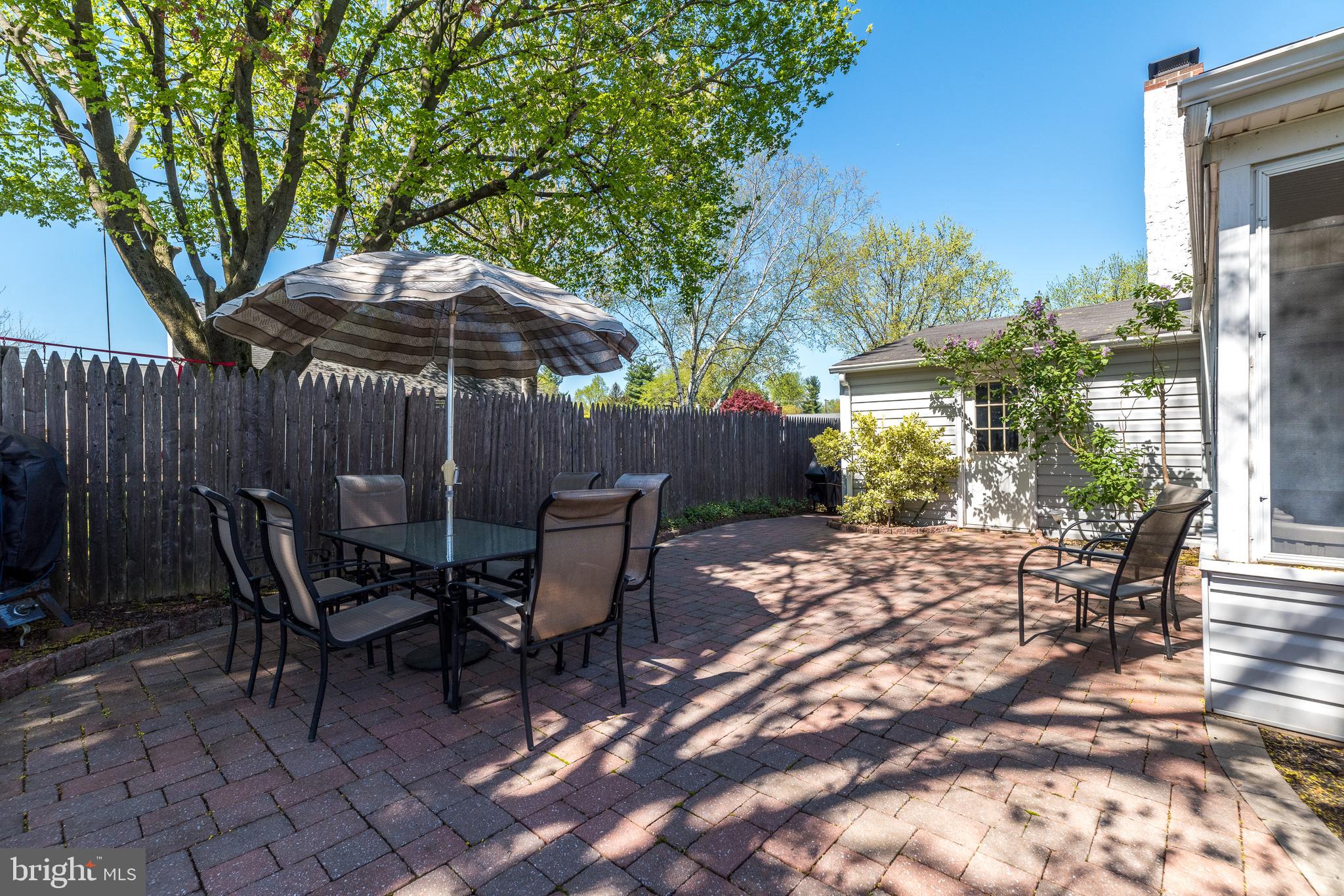 231 Parry Road Warminster, PA 18974 - Photo 60 of 71 a view of a patio with table and chairs under an umbrella with wooden fence