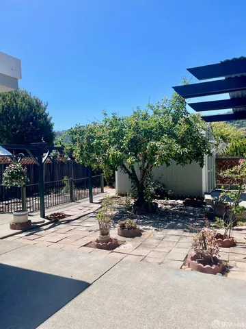 a backyard of a house with table and chairs with wooden fence and plants