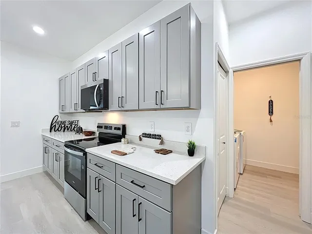 a kitchen with a sink a stove a refrigerator and white cabinets