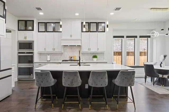 a kitchen with stainless steel appliances granite countertop a table chairs sink and cabinets
