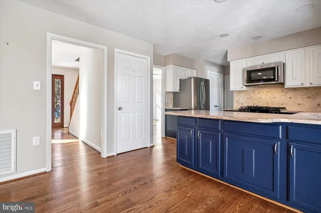 an empty room with wooden floor fireplace and windows