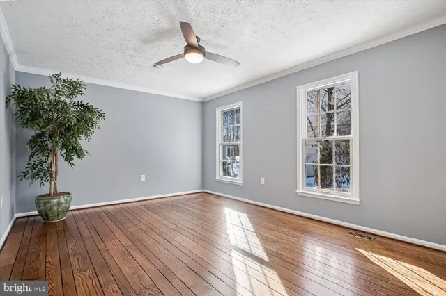 a view of empty room with wooden floor and fan