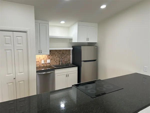 a kitchen with granite countertop a refrigerator and a stove top oven
