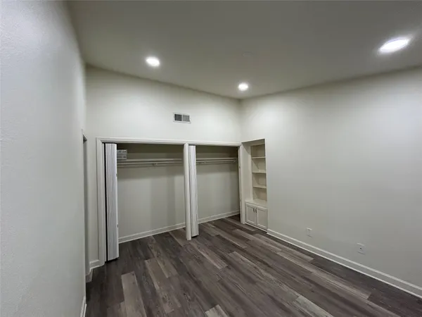 an empty room with wooden floor & closet and windows