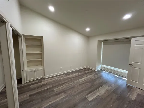 a view of an empty room with wooden floor and closet