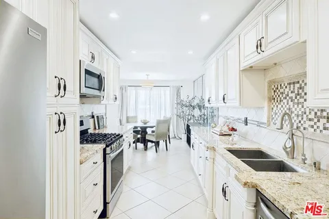 a kitchen with granite countertop a sink a counter top space appliances and cabinets