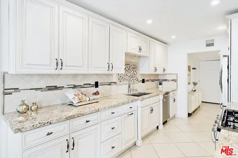 a kitchen with granite countertop white cabinets white stainless steel appliances with a sink and dishwasher