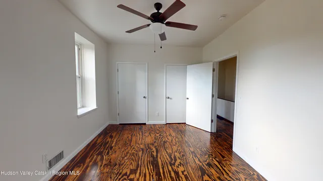 a view of empty room with wooden floor and fan
