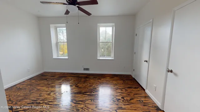 a view of an empty room with window and wooden floor