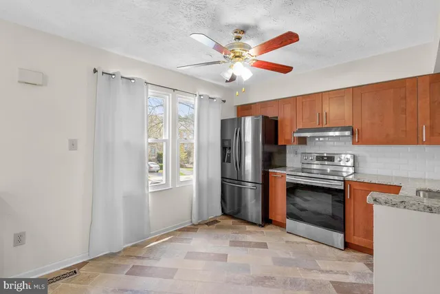 a kitchen with stainless steel appliances granite countertop a refrigerator a stove a sink and dishwasher