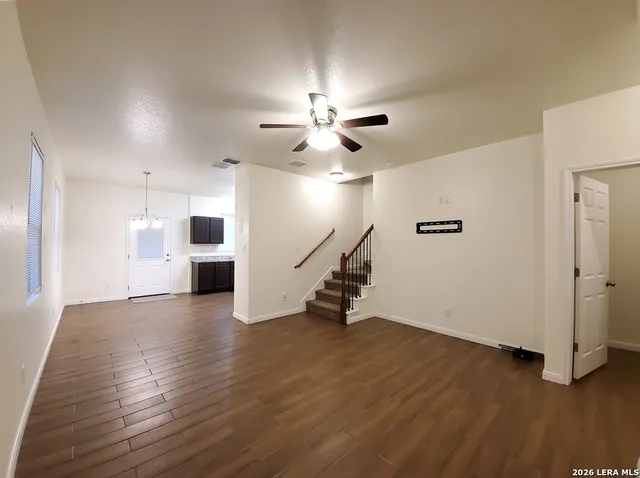 a view of an empty room with wooden floor and a ceiling fan