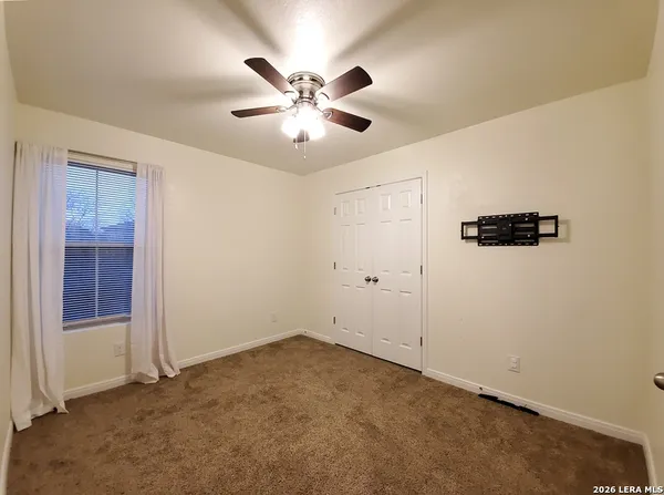 an empty room with windows and fan