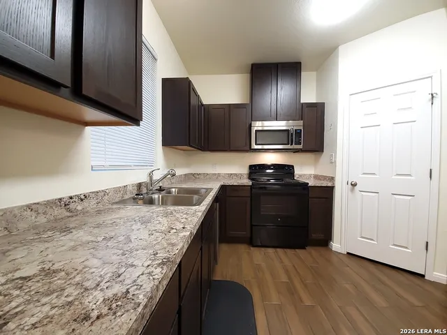 a kitchen with granite countertop wooden cabinets and black stainless steel appliances