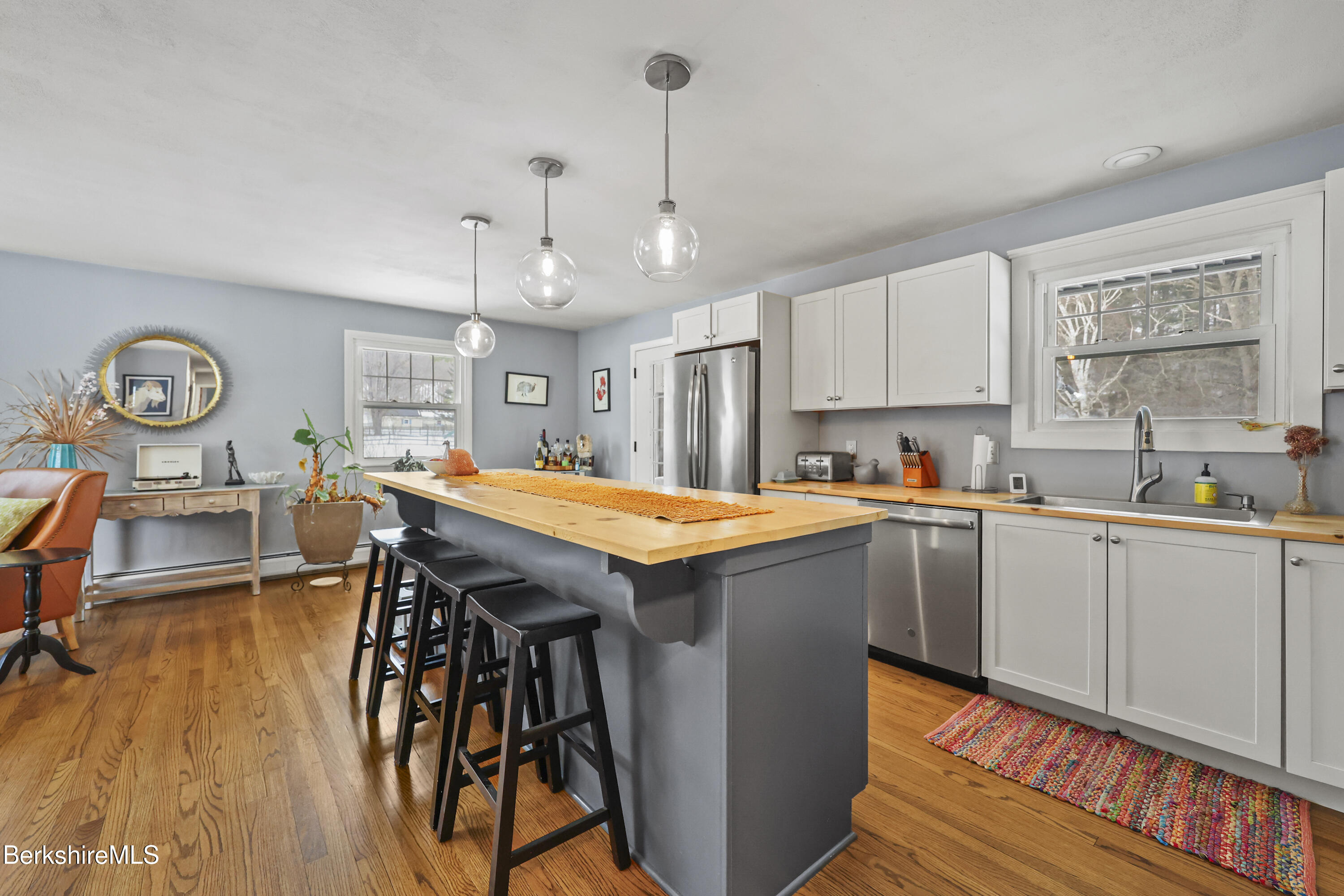 184 Washington Mountain Road Lee, MA 01238 - Photo 14 of 42 a kitchen with stainless steel appliances granite countertop a kitchen island a stove a sink a dining table and chairs with wooden floor