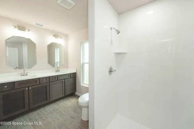 a spacious bathroom with a double vanity sink toilet mirror and double