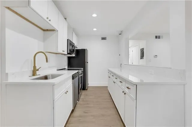 a kitchen with white cabinets a sink dishwasher and a stove with wooden floor