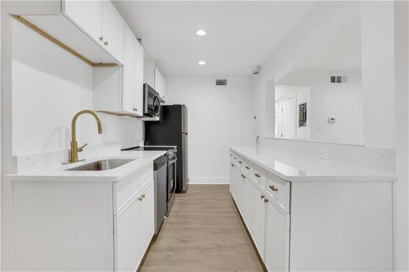 2396 Lawrenceville Highway, Unit V Decatur, GA 30033 - Photo 10 of 27 a kitchen with white cabinets a sink dishwasher and a stove with wooden floor