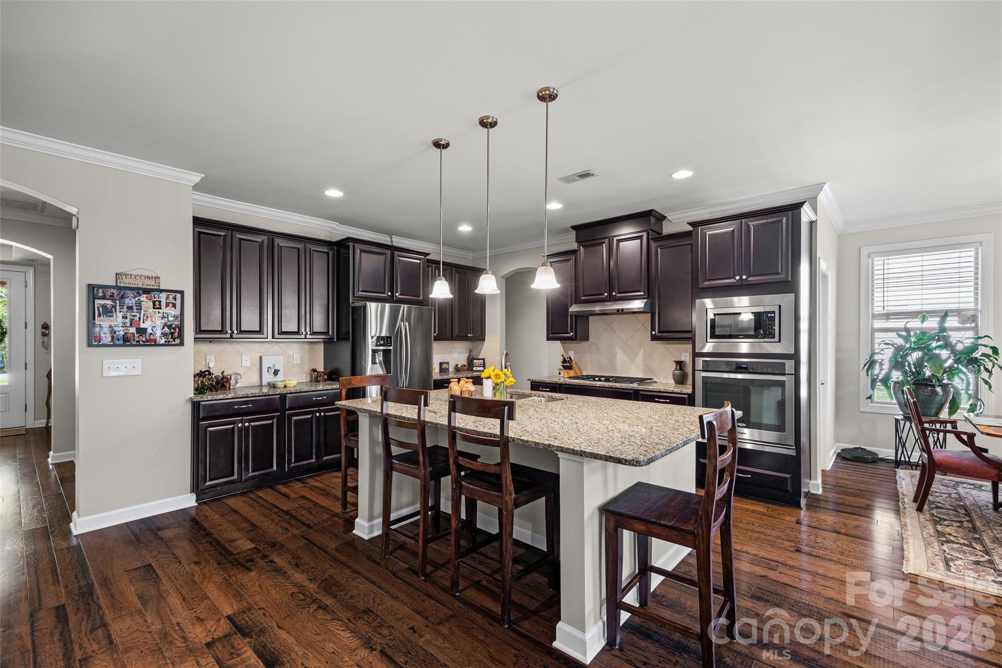 2054 Lometa Road York, SC 29745 - Photo 9 of 45 a kitchen with stainless steel appliances granite countertop a stove top oven a refrigerator a sink and a dining table with wooden floor