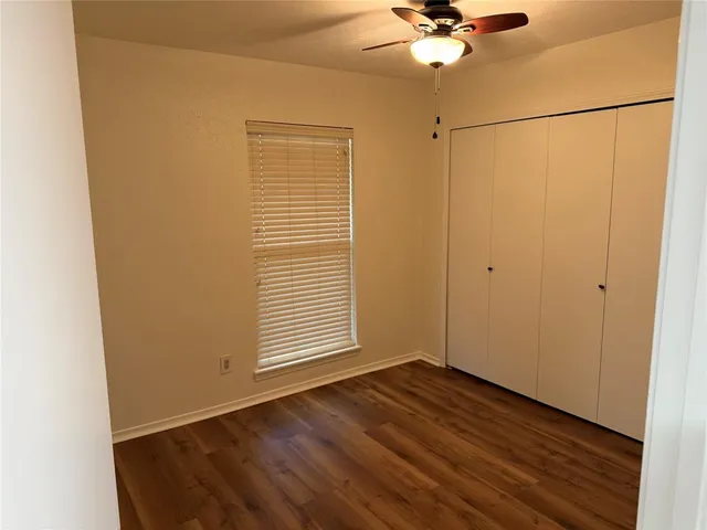 an empty room with a ceiling fan and wooden floor