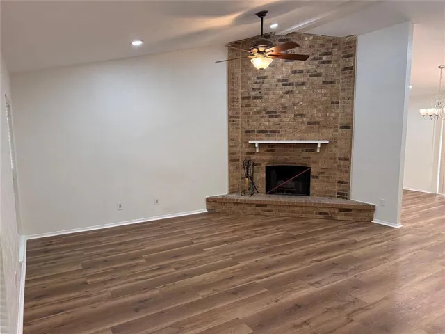 an empty room with wooden floor fireplace cabinet and windows