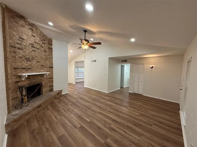 an empty room with a fireplace and chandelier fan