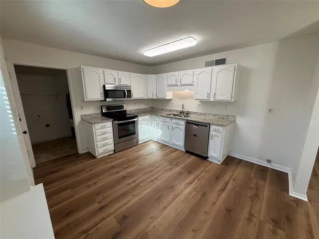 a kitchen with wooden floors and white appliances