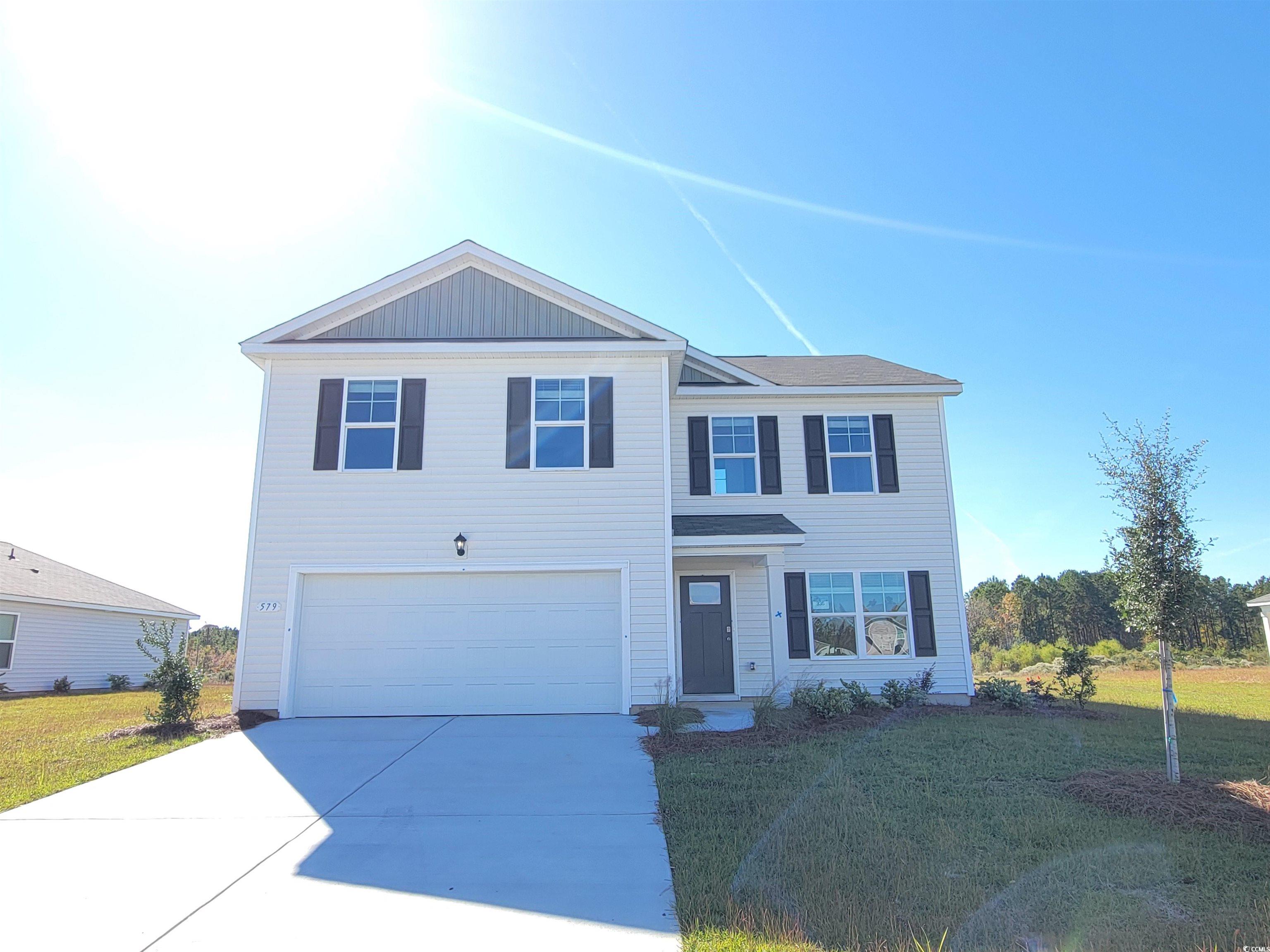 Traditional-style home featuring a front lawn, concrete driveway, and an attached garage