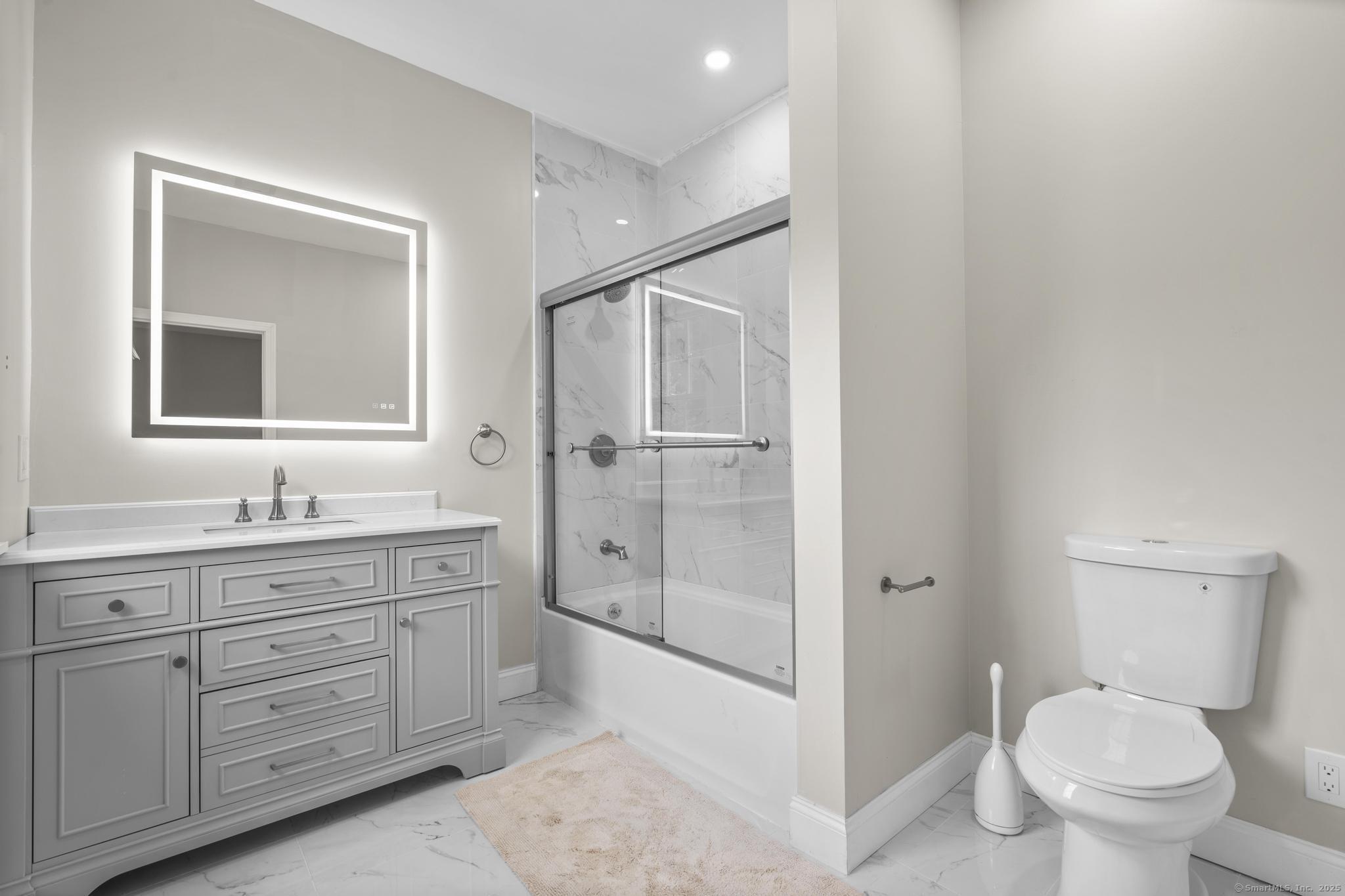 424 Racebrook Road Orange, CT 06477 - Photo 20 of 36 a bathroom with a toilet a sink a glass door a shower a mirror and vanity