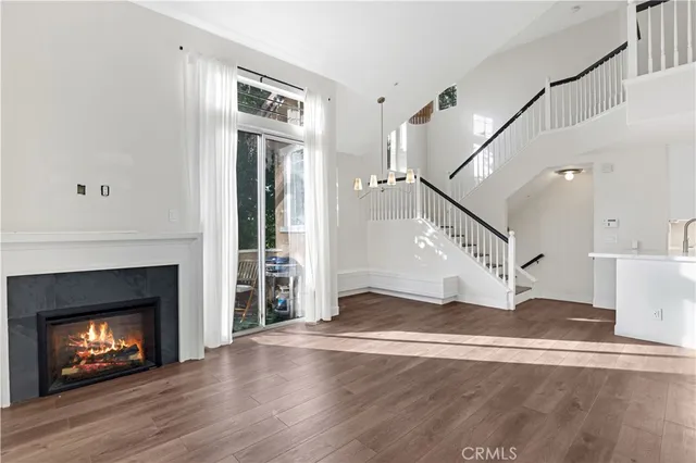 a view of an empty room with wooden floor fireplace and a window