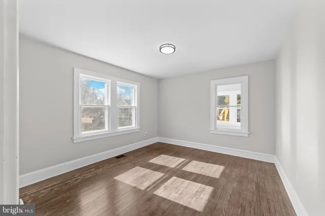an empty room with wooden floor chandelier fan and windows