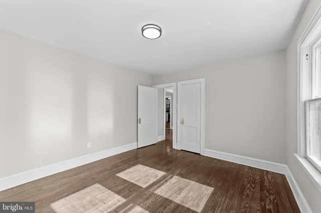 a view of empty room with wooden floor and ceiling fan
