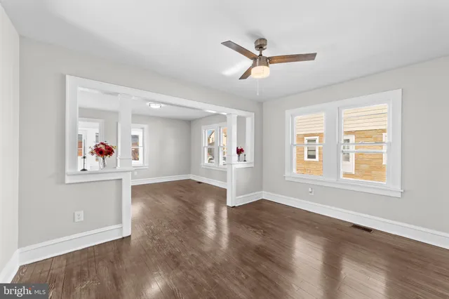 an empty room with wooden floor and windows