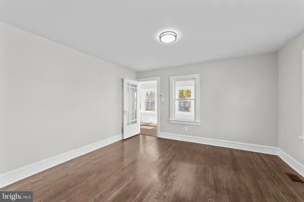 a view of an empty room with a window and wooden floor