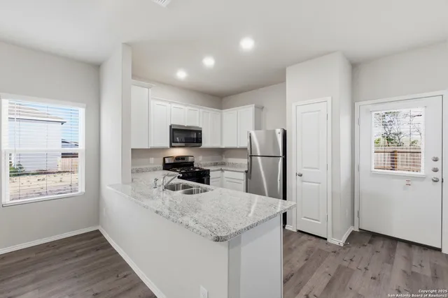 a kitchen with stainless steel appliances granite countertop a refrigerator oven a sink dishwasher and wooden floor