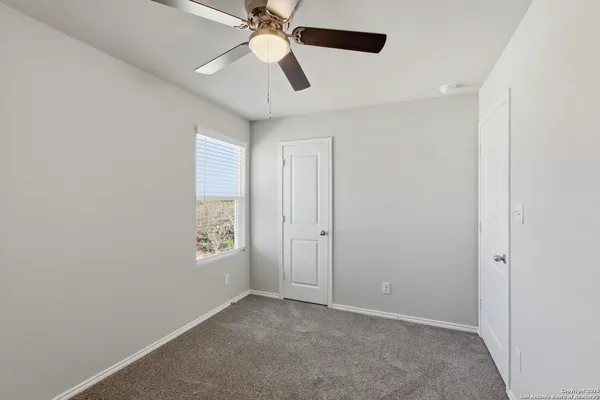 an empty room with windows and fan