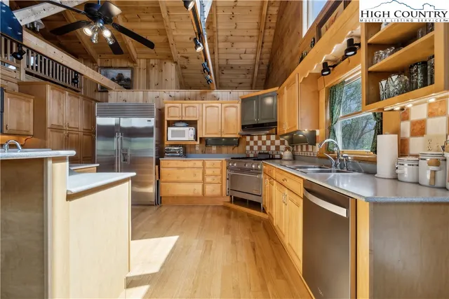 a kitchen with stainless steel appliances granite countertop a sink a stove and a wooden cabinets