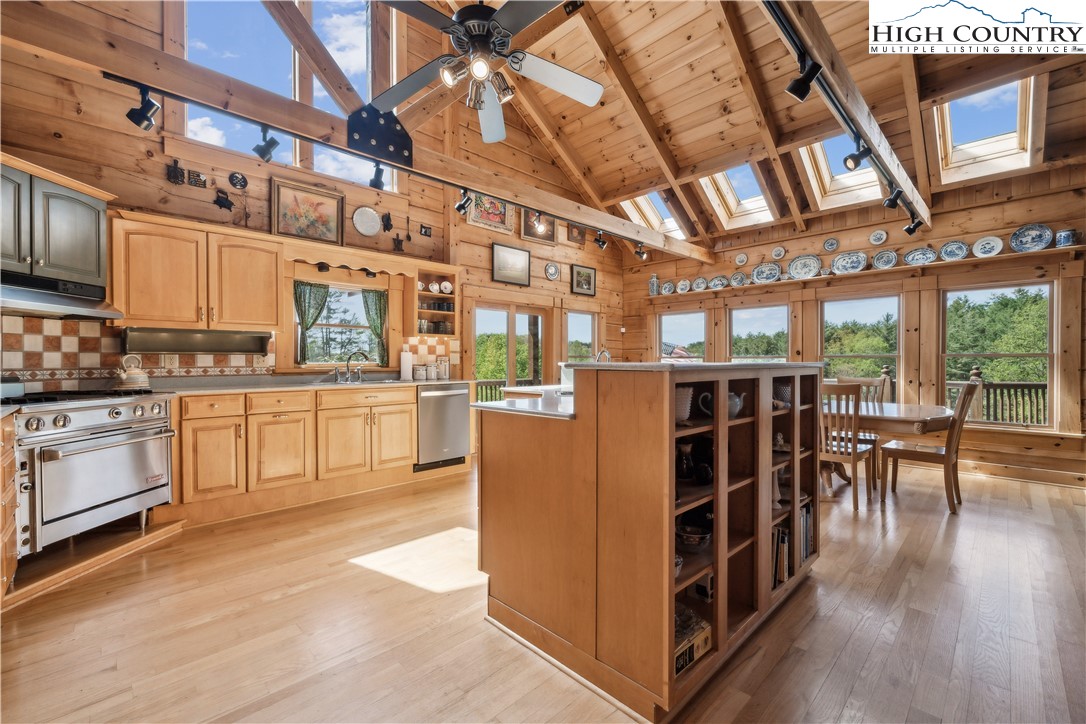 101 Double Branch Road Grassy Creek, NC 28631 - Photo 15 of 50 a kitchen with stainless steel appliances kitchen island granite countertop a stove a refrigerator a dining table and chairs with wooden floor