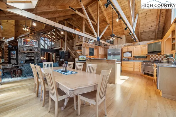 a dining room with stainless steel appliances kitchen island granite countertop a table chairs and a wooden floor