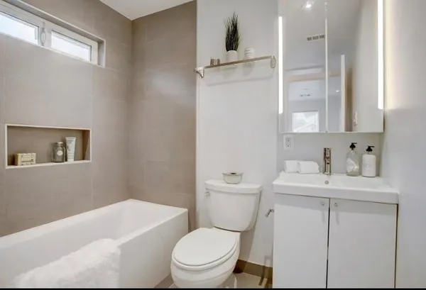 a bathroom with a toilet a sink a mirror and vanity
